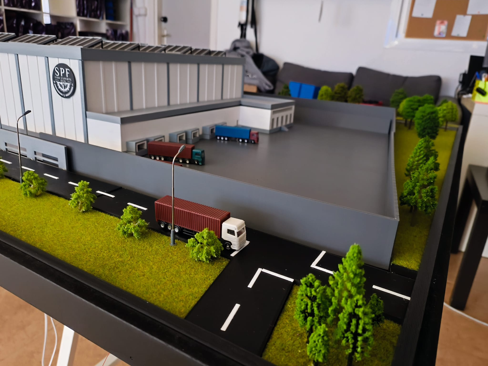 Maqueta de instalación logística e industrial impresa en 3D con camiones y vegetación